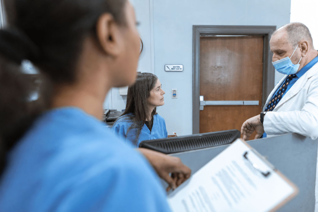 Drei Mitarbeitende im Krankenhaus an einer Pflegestation